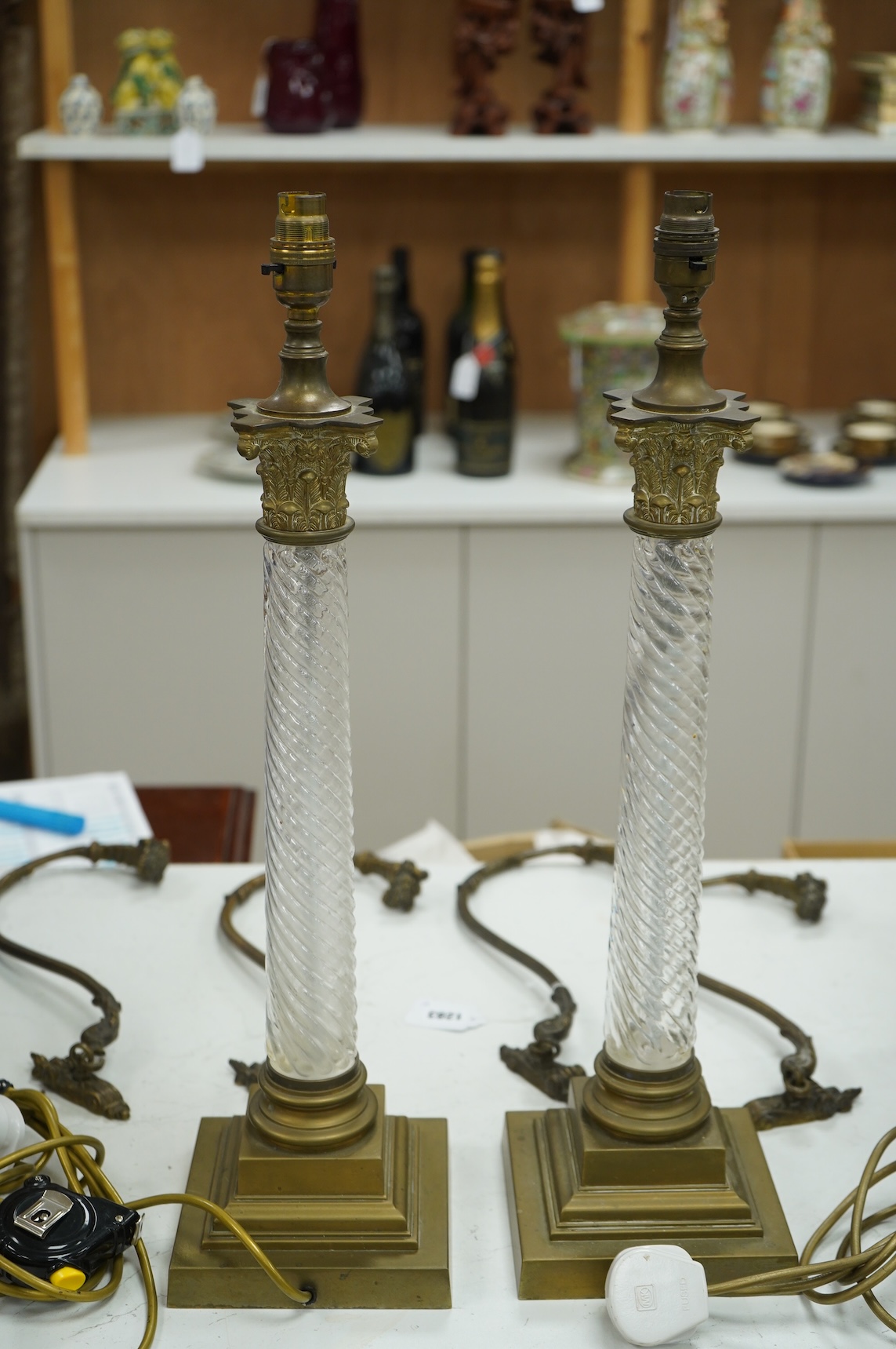 A pair of brass and glass Corinthian column lamps, 59cm high overall
